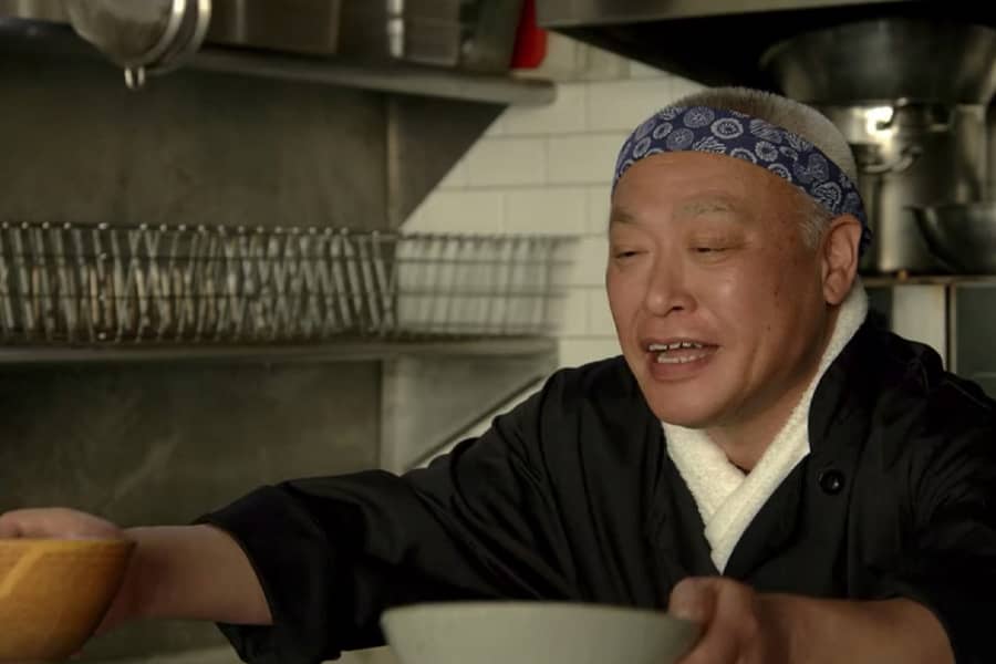 Japanese chef hands two bowls across the counter