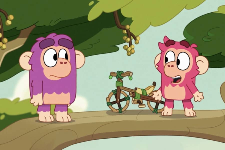 Chunky, in a tree, shows his bike invention to another chimp