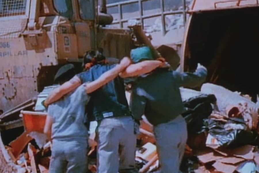 three workers embrace at the dump