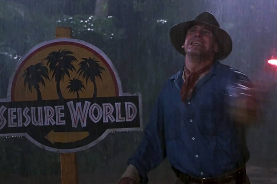 a paleontologist waves a flare in the rain next to a sign that says “Seisure World”