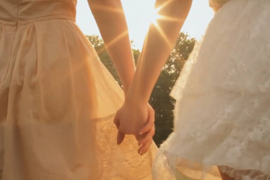 closeup of the women holding hands with the sun shining behind