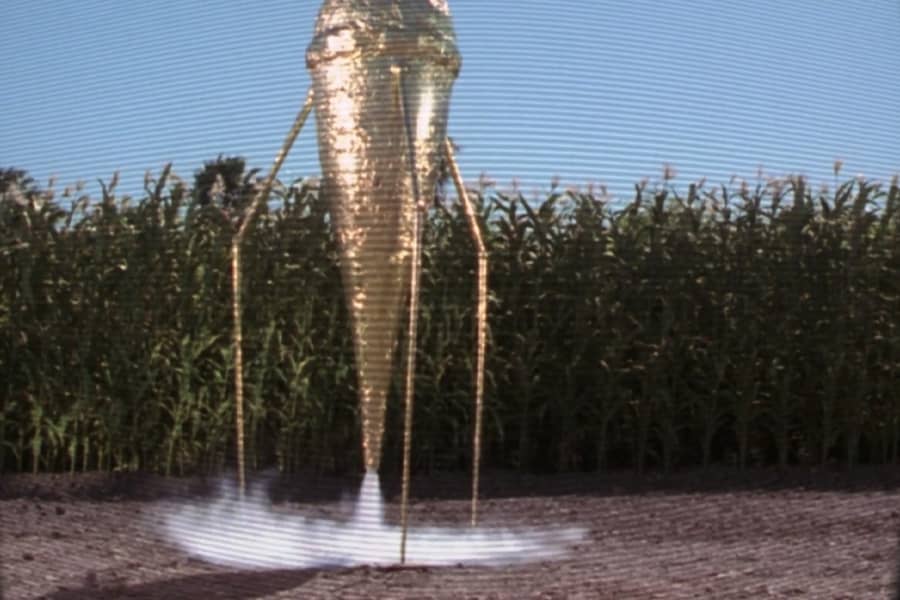 a golden ice cream cone-looking spaceship lands in the cornfield