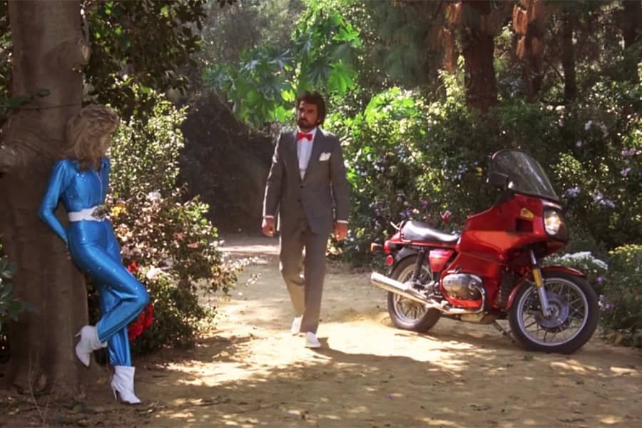 Pee Wee approaches Dottie from a slick red motorbike