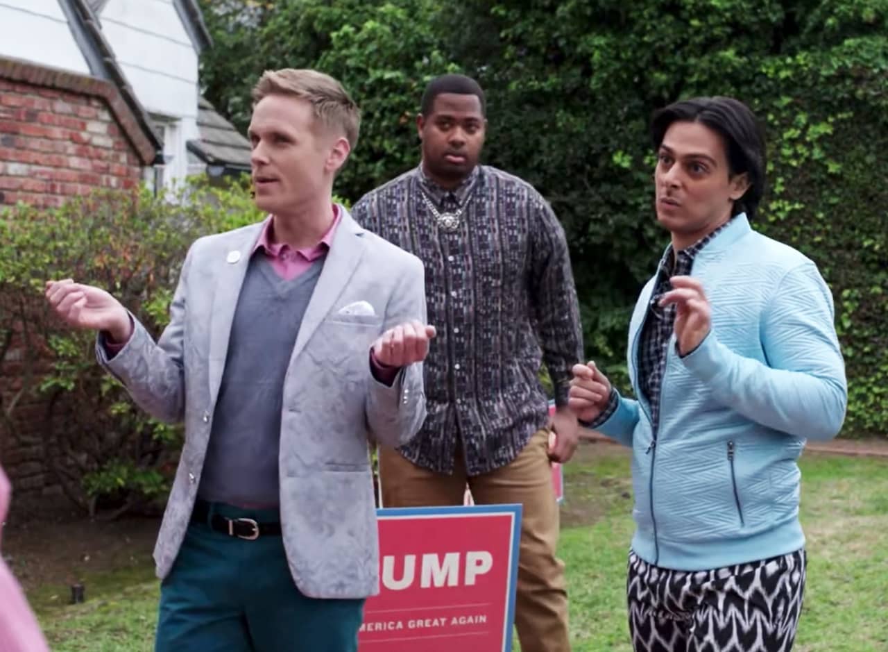 three men stand outside a home with a Trump lawn sign