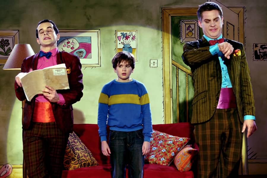 hosts with a kid on a fake living room set