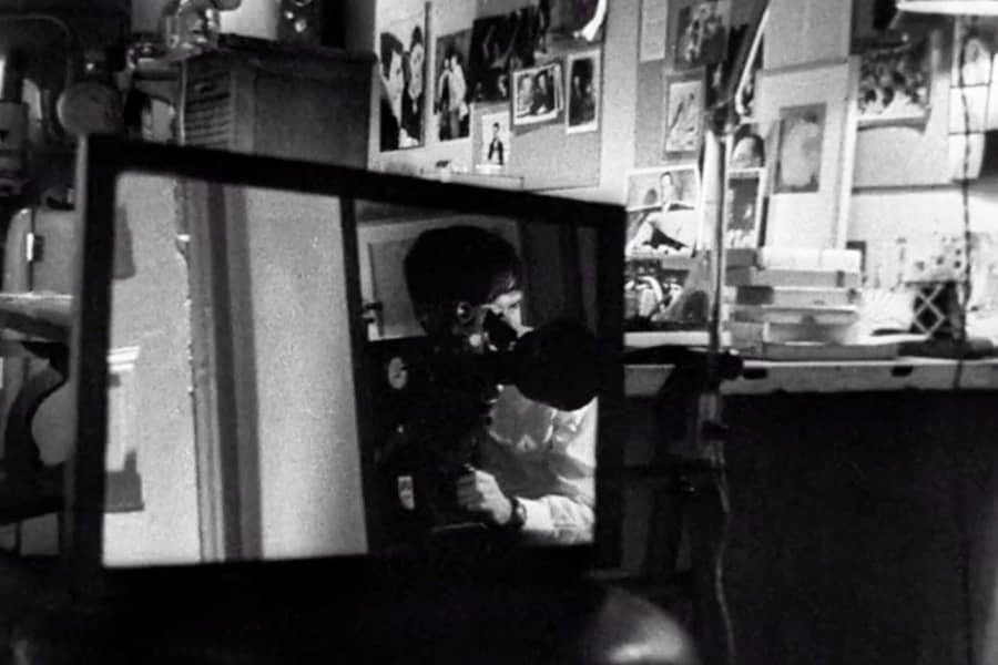 a man’s reflection in a mirror films from behind a camera