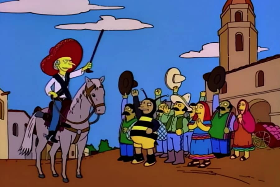 a crowd in a Mexican village (including a man in a bumble bee costume) cheer on Mr. Burns