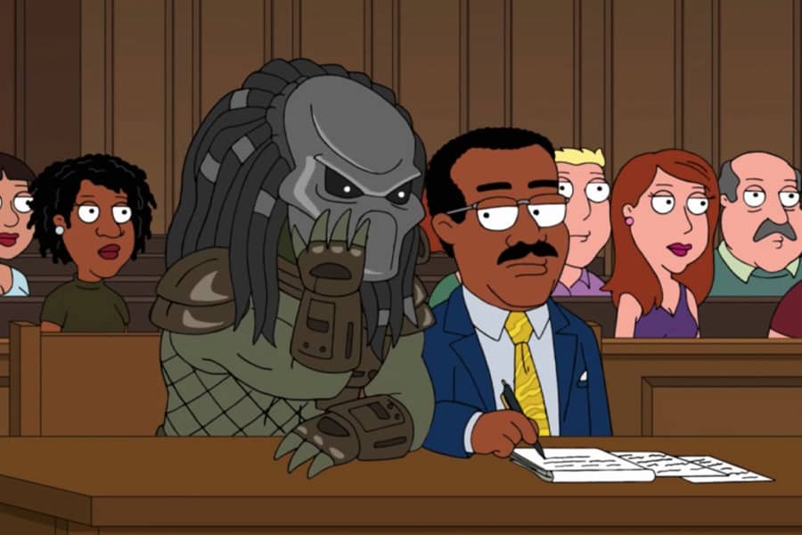 Predator, in a courtroom, leans to whisper something to Johnnie Cochran