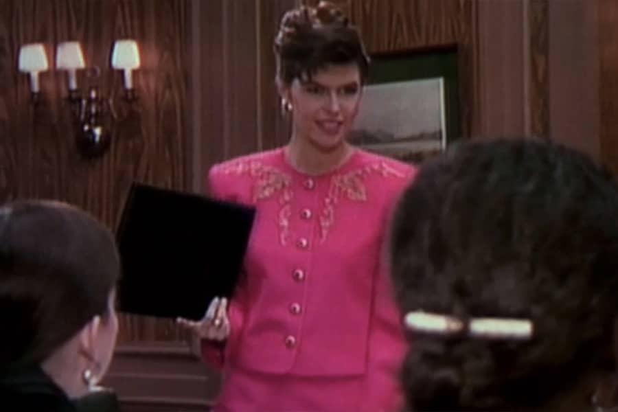 protagonist in a pink suit holding a folio