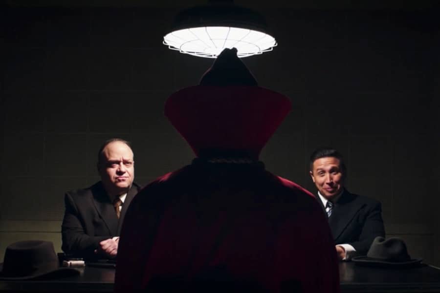 the back of Hooded Justice as he is interrogated by two detectives