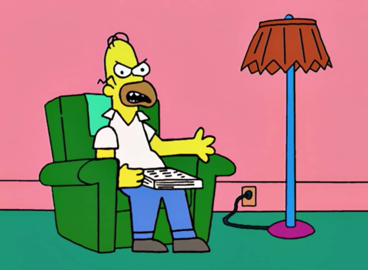 a poorly drawn Homer Simpson looks angry as he sits on a recliner