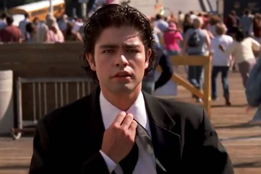 Vincent Chase as Arthur Curry looks off in the distance and begins undoing his necktie