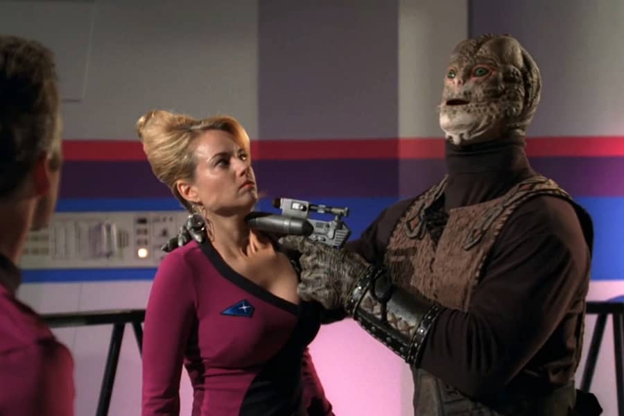 Gorth holds a weapon up to Yeoman Malloy’s neck