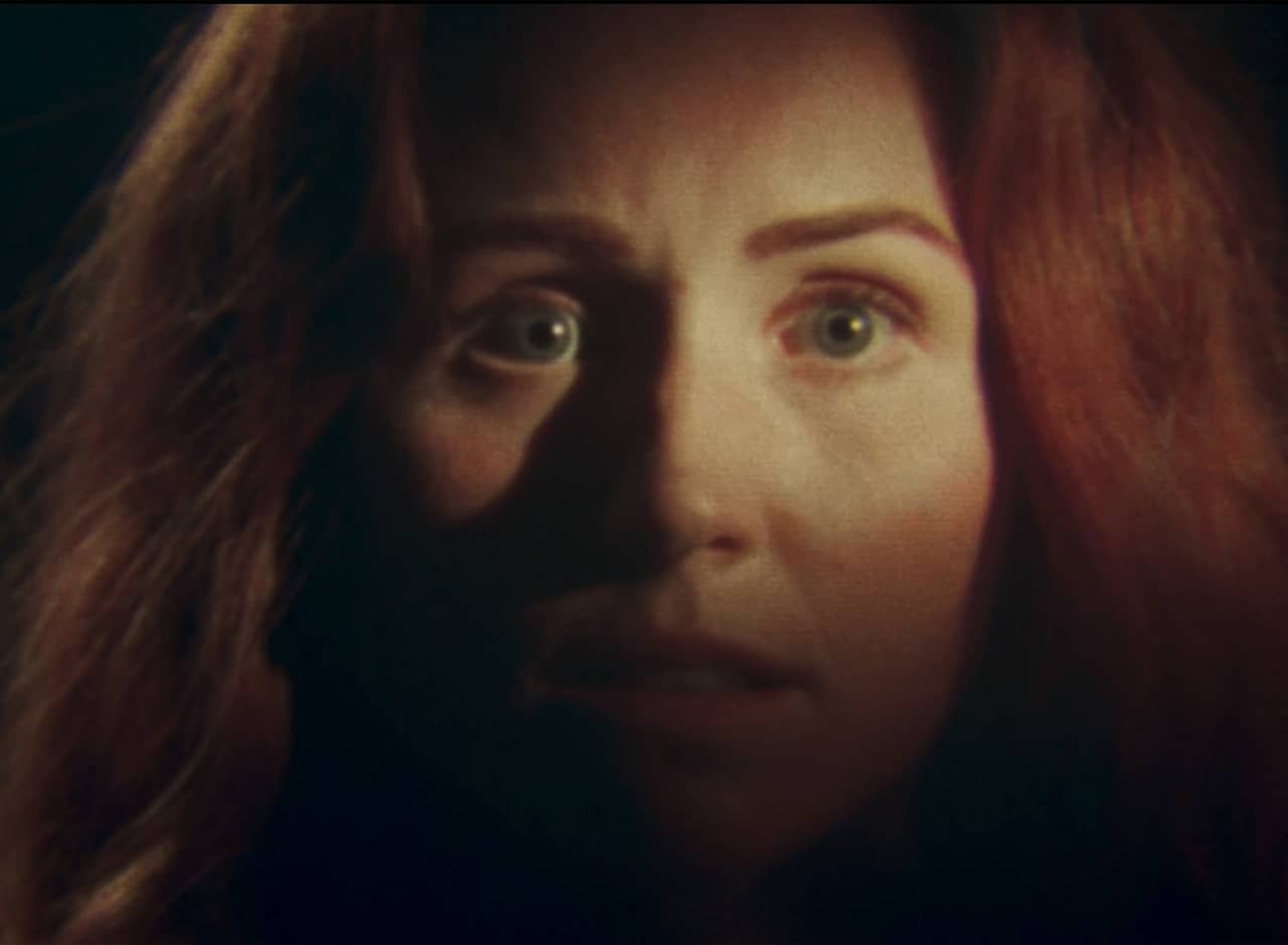 Alice Lee, a woman with red curly hair staring into the camera