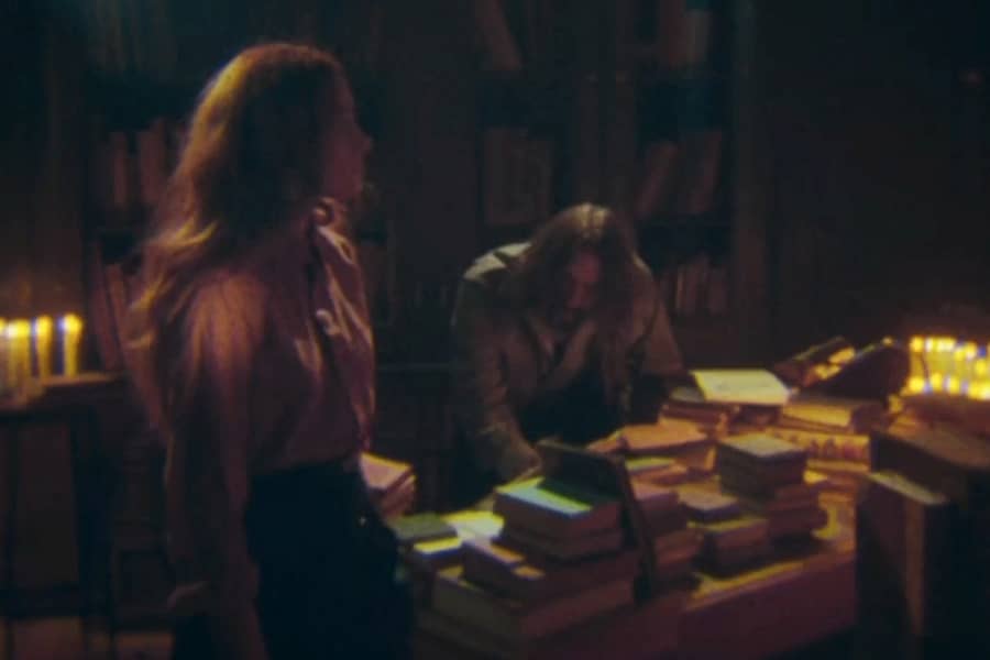 man reading from books as woman stands nearby