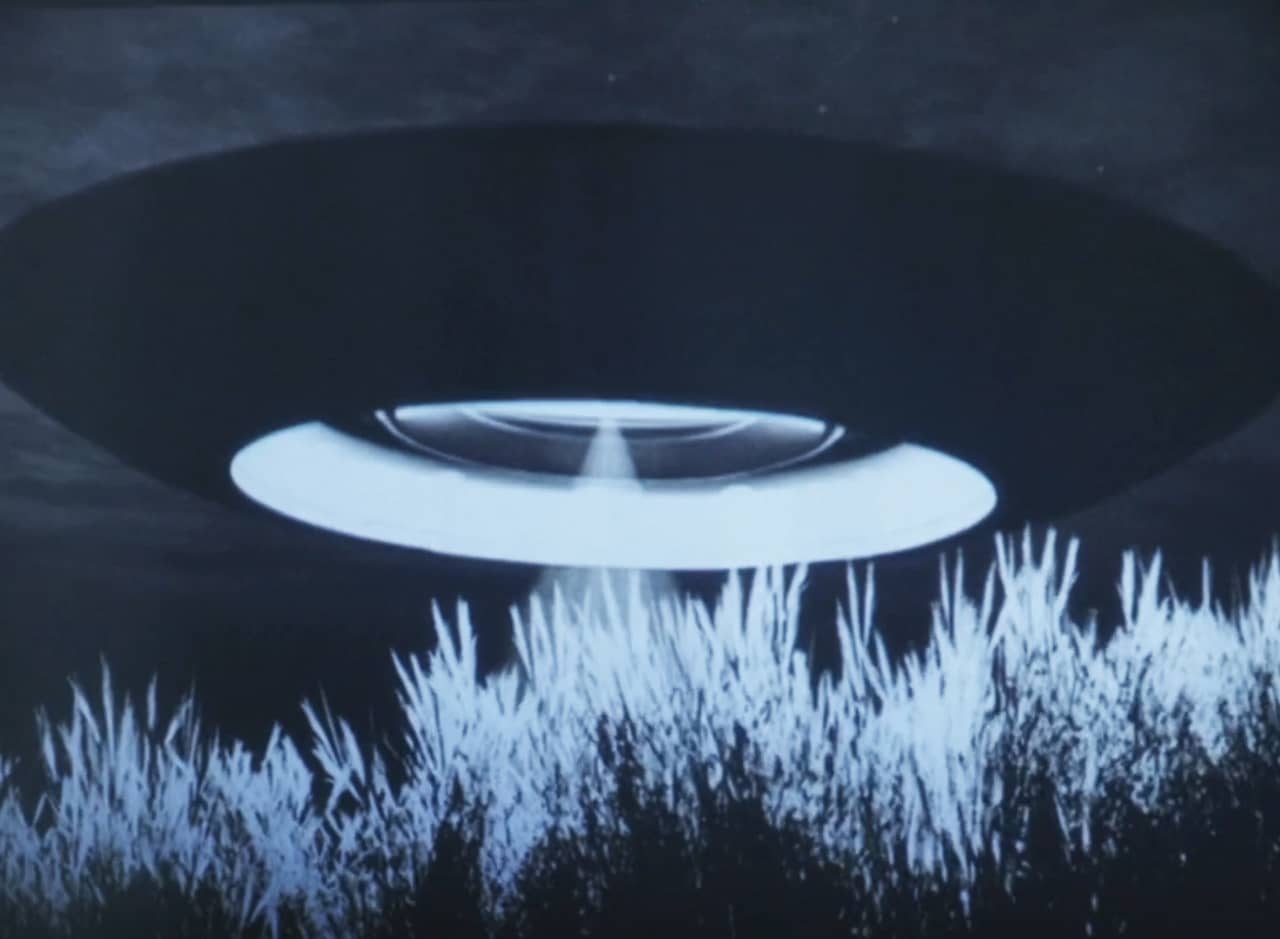 UFO hovering above some tall grass