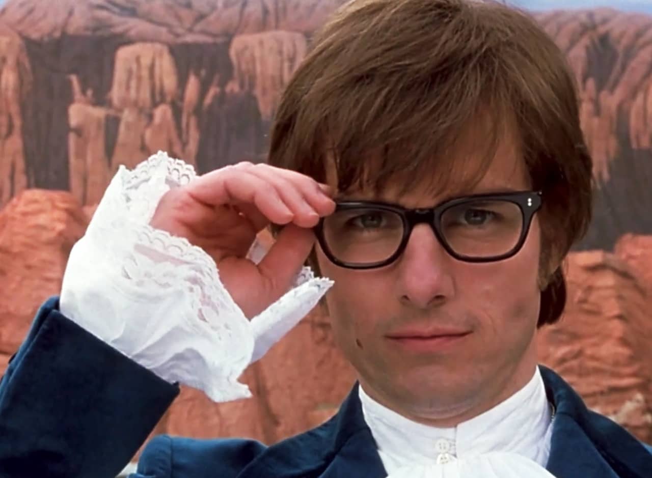 Tom Cruise dressed as Austin Powers in thick glasses and ruffly shirt