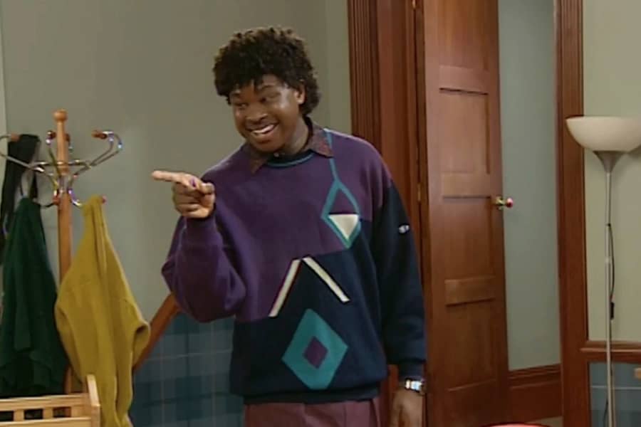 Lavetrious Kennedy in a colorful 80s sweater and pointing