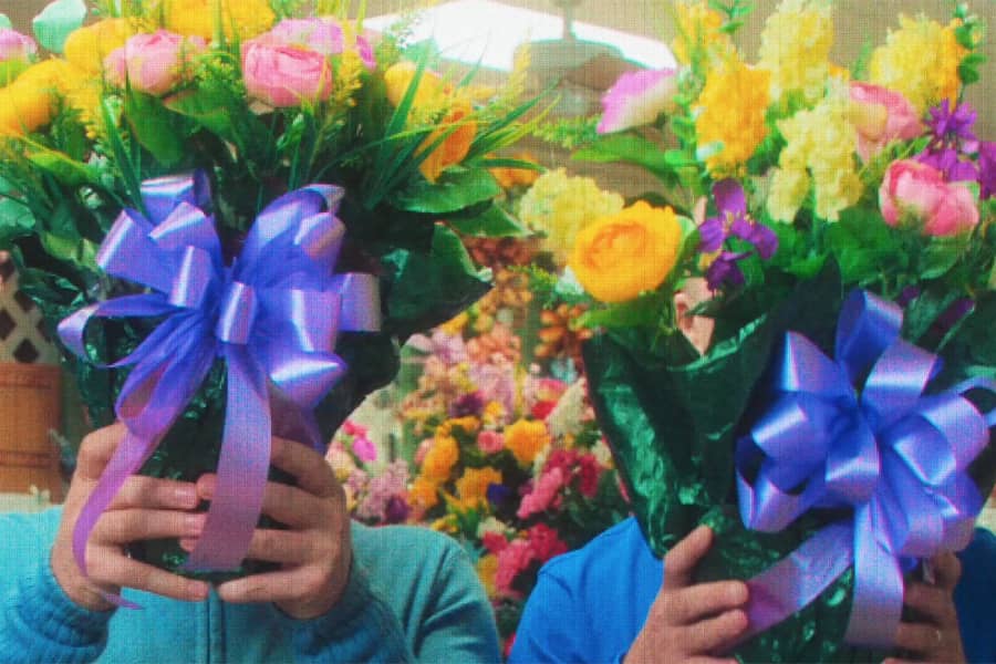 hands holding two big bouquets with bows on them