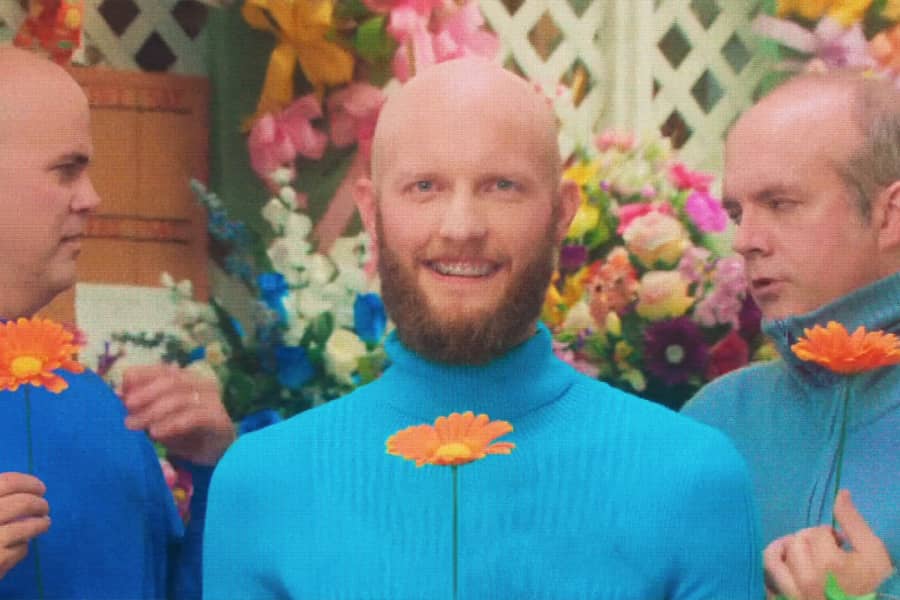 Rick smiling and holding a flower, Mr. Steve and Mr. Mike looking at each other disgusted