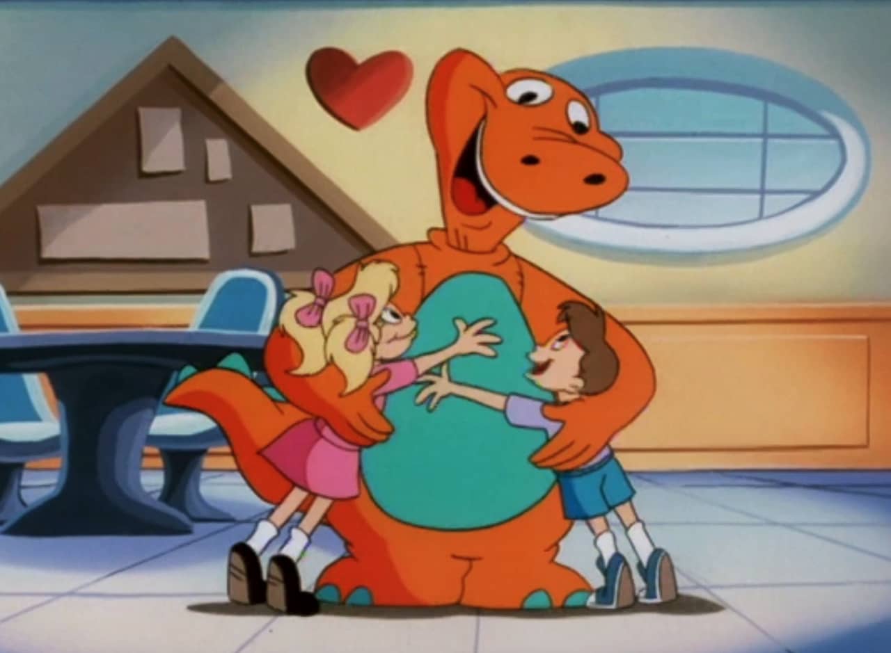 Baloney, a big orange dinosaur, hugging two kids in a classroom