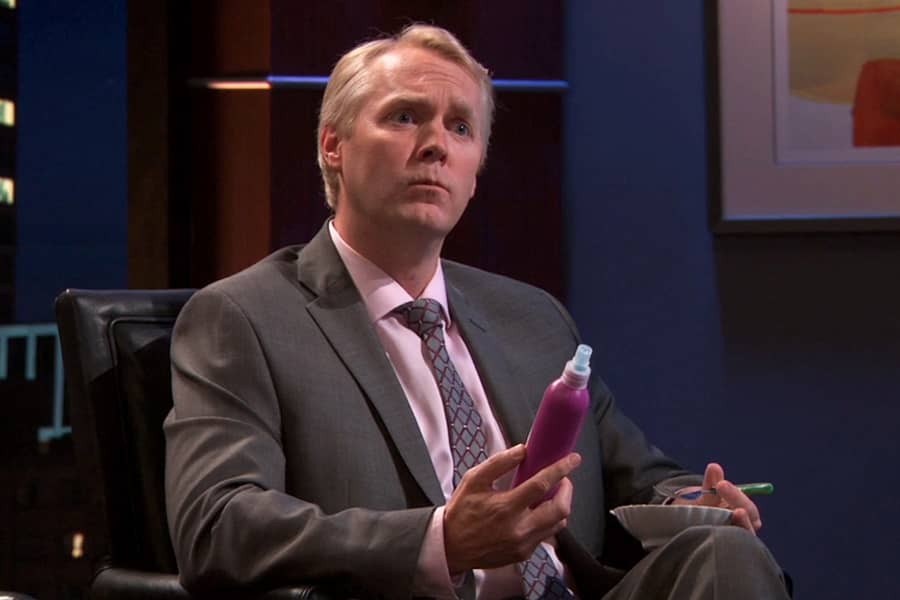 white man billionaire holding a purple product bottle