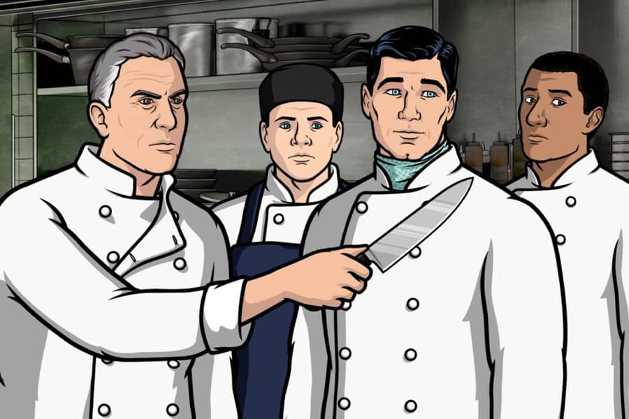 Casteau holding up a knife near his chef team