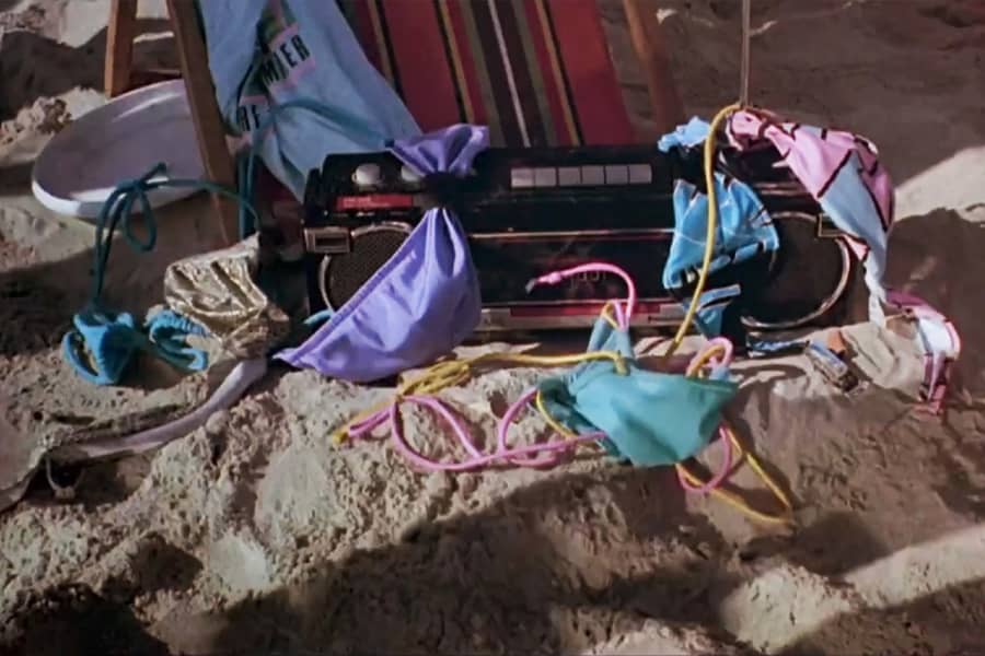 bikini tops strewn on a boombox on the sand