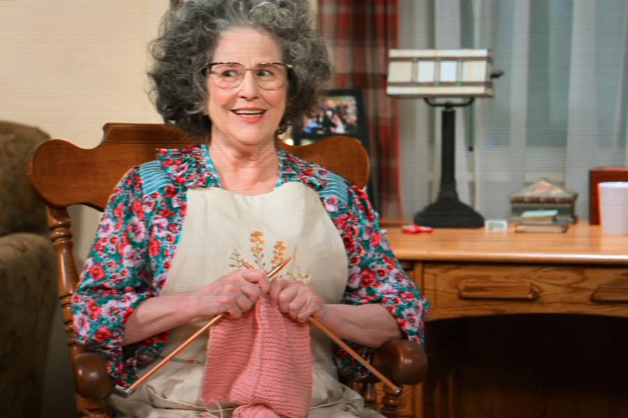 grandmother smiles while holding her knitting needles