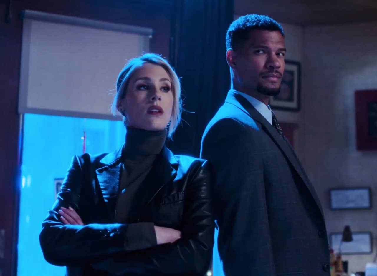 Detective Green, a white woman with blonde hair, and her partner Detective Turner, a black man, strike a pose in a doorway
