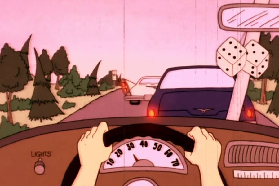 hands on a steering wheel with two cars in front