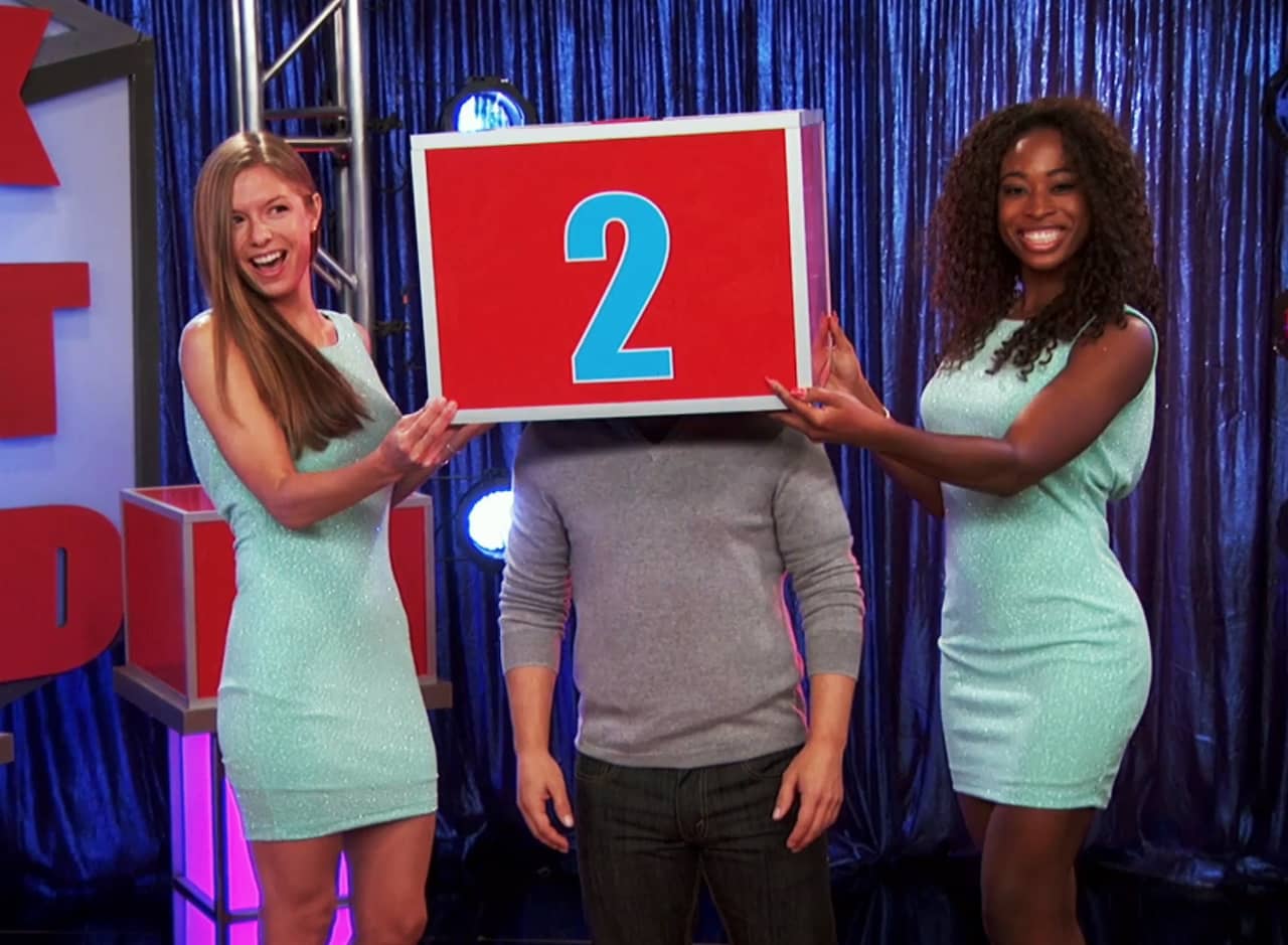 two women helpers holding a box labeled 2 over the head of a teen boy
