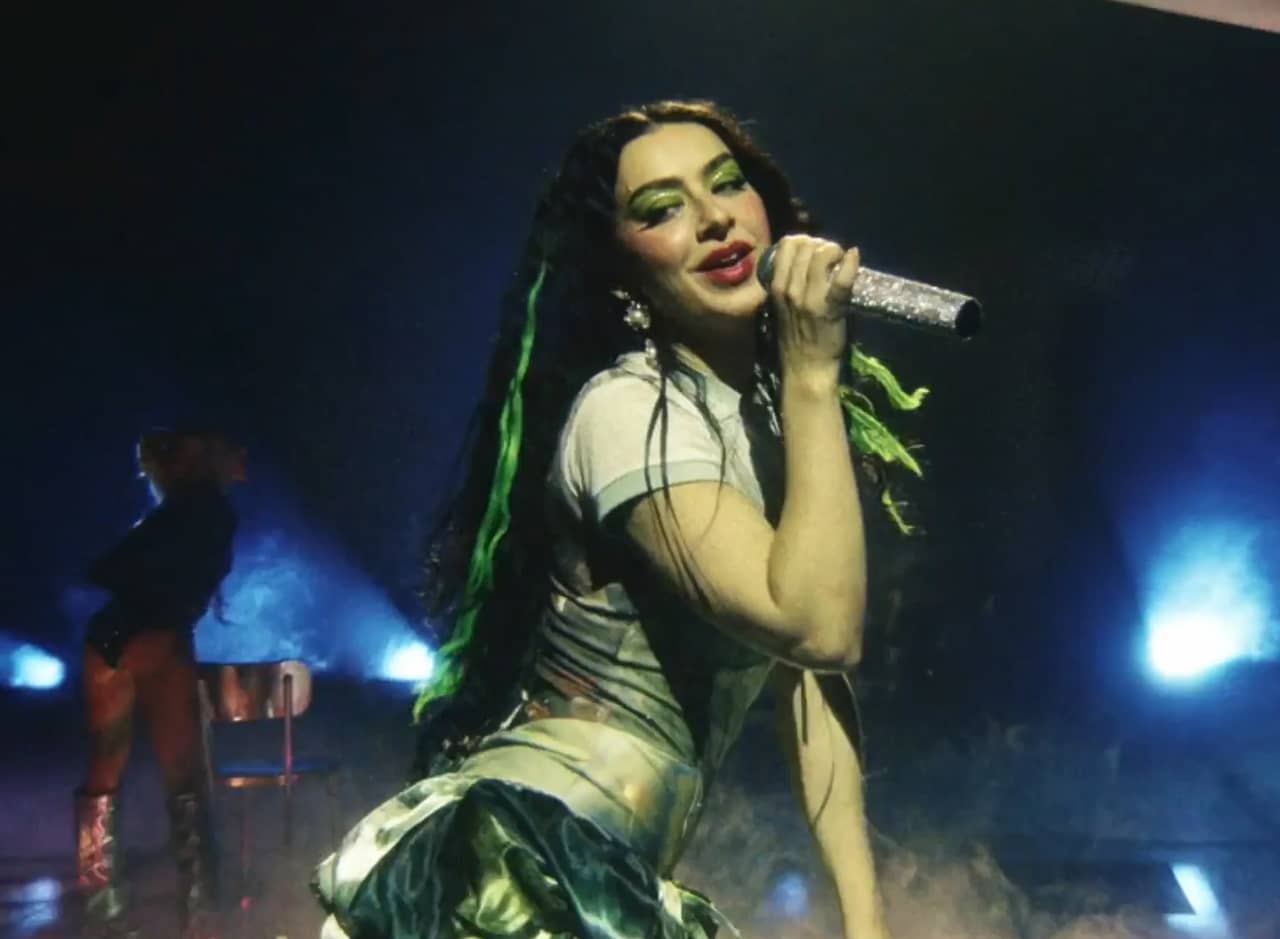 Charli xcx on stage holding a glittery microphone