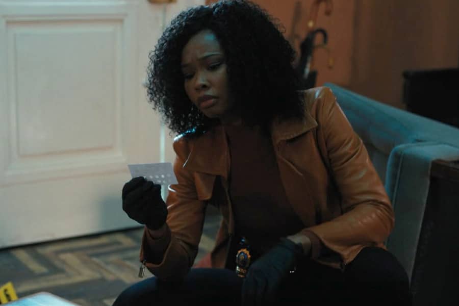 Naomi Jackson as the new Brazzos, a black woman detective inspecting some evidence