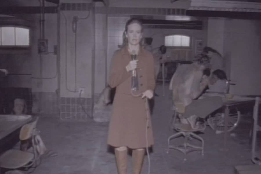 Winters standing in a bleak concrete room with patients around