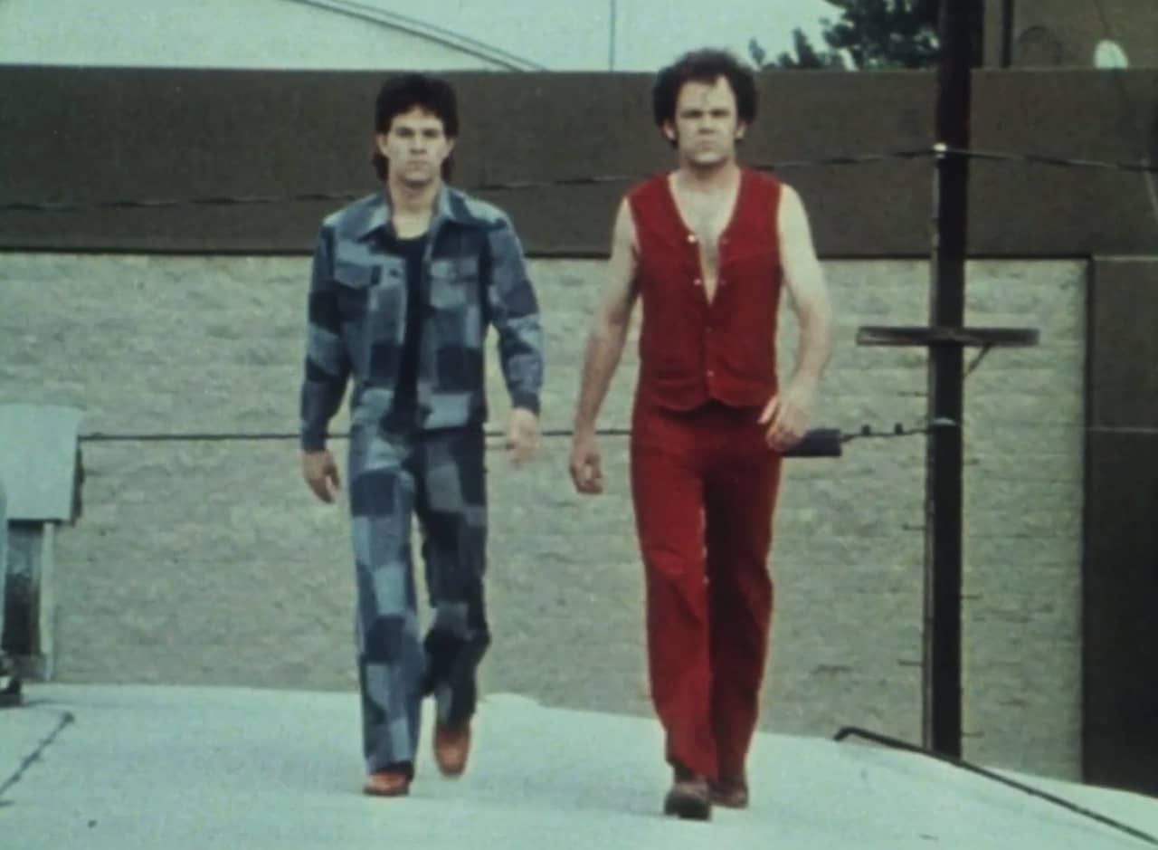 Brock Landers and Chest Rockwell, in audacious 1970s suits, walk toward the camera