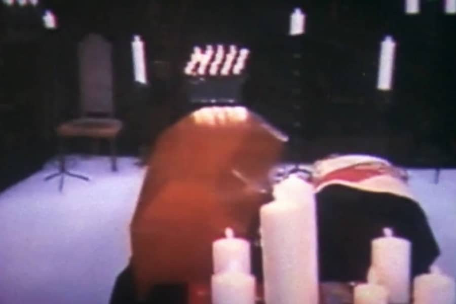 a low-budget set featuring a coffin surrounded by candles