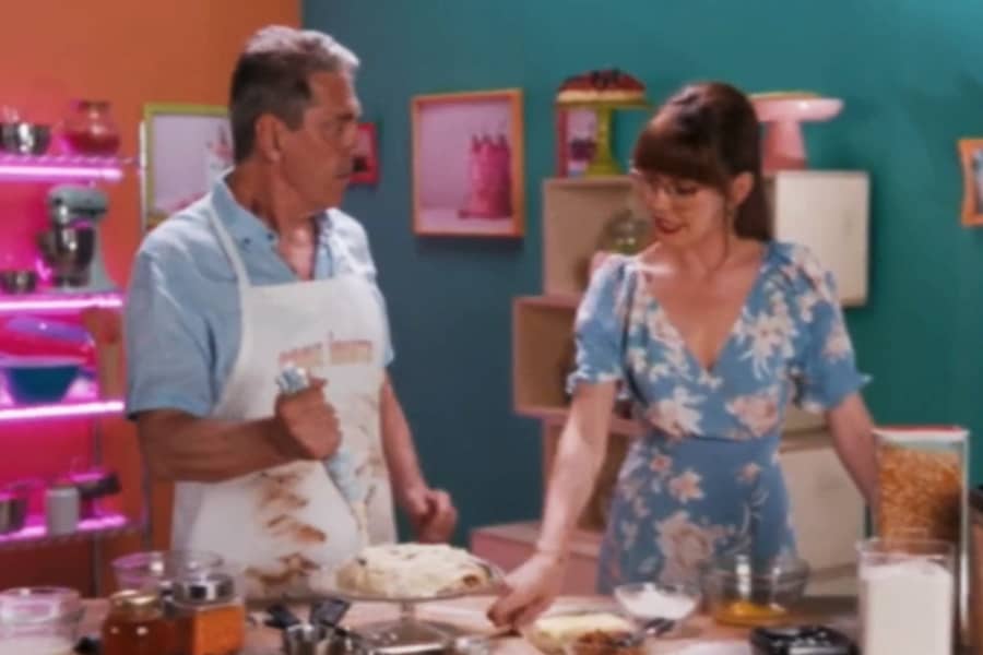 host talking with a baker piping frosting on a cake