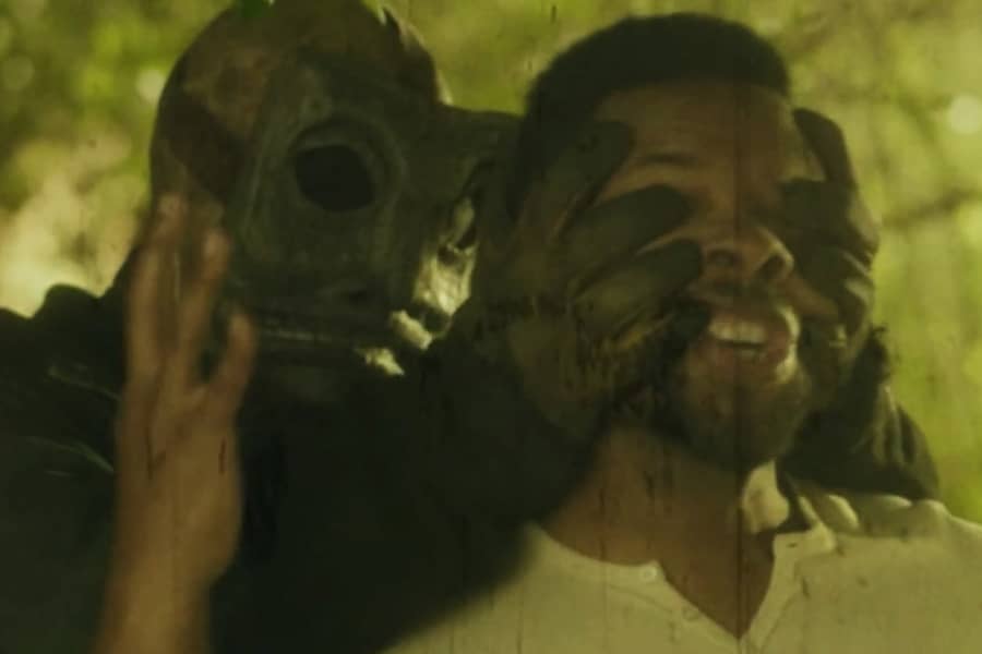 a man wearing a mask and gloves grabs the face of a terried male counselor