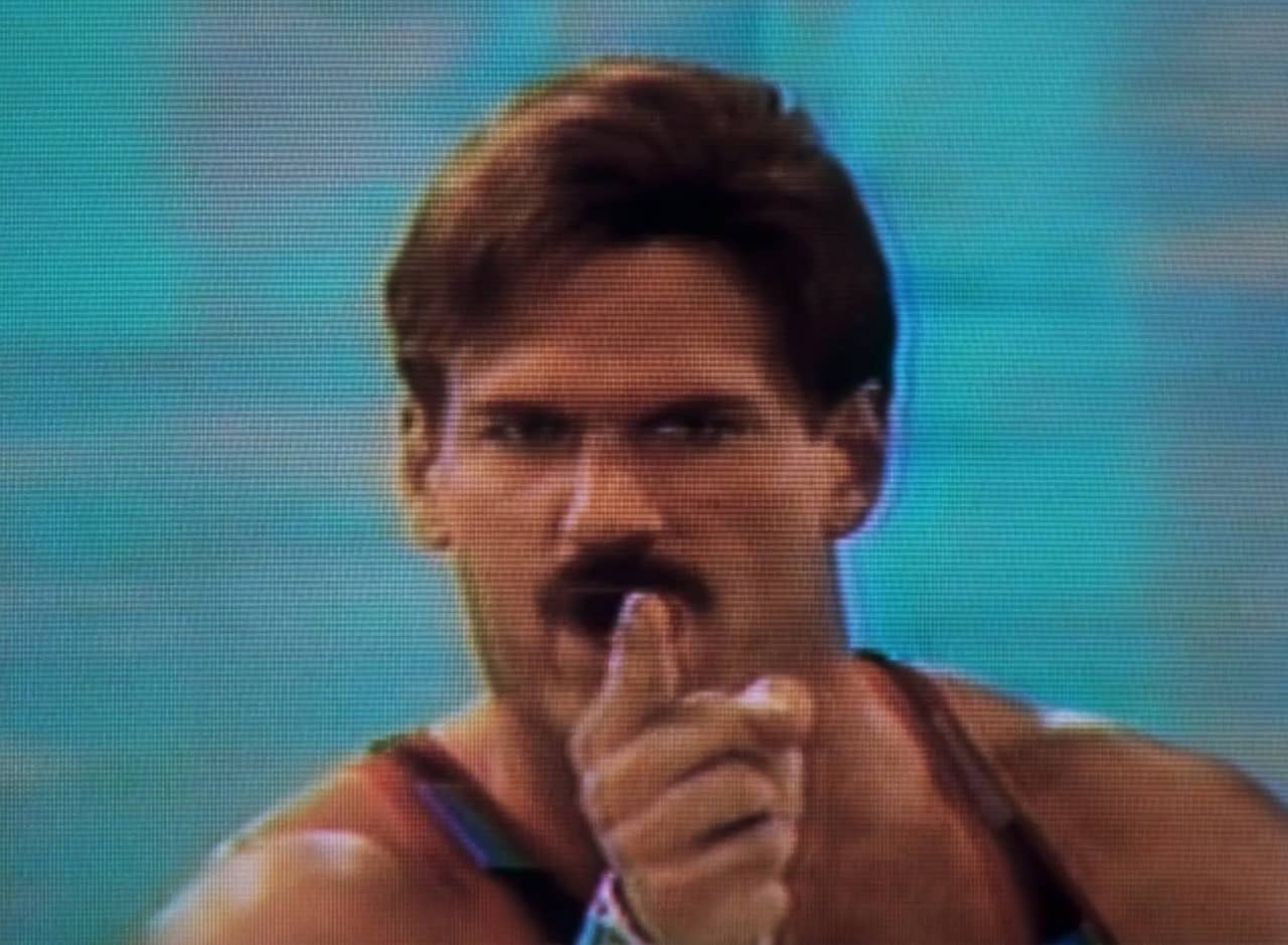 Captain Freedom, mustached man in gym spandex, pointing at the camera