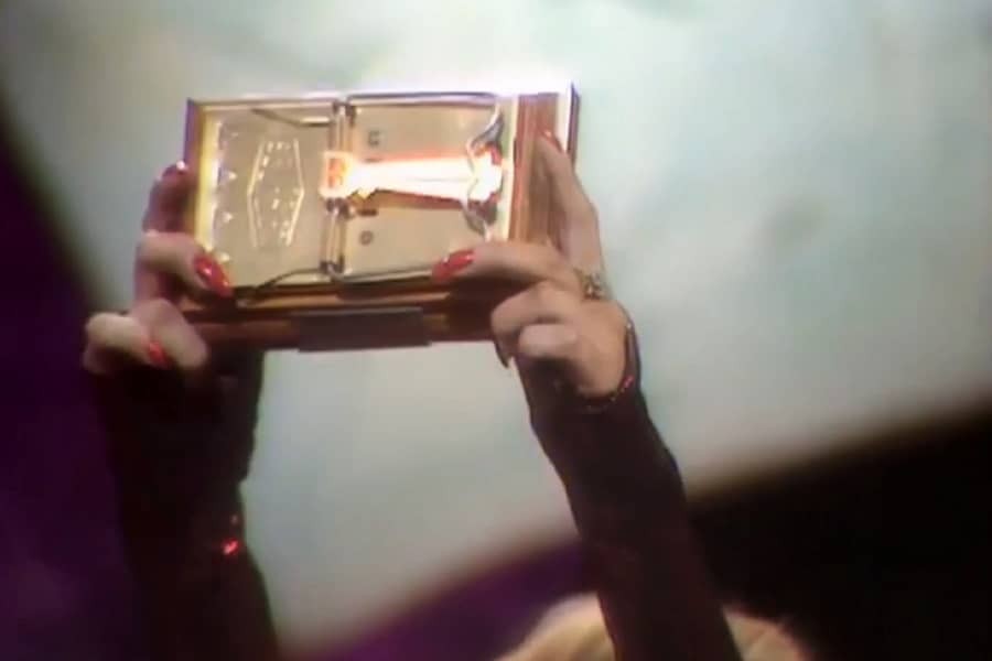 assistant holds up a golden mouse trap