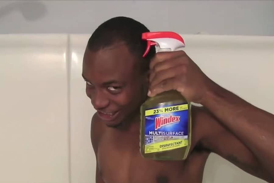 Charley in the shower holding up a bottle of Windex