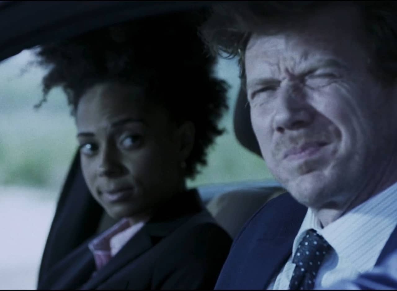 two detectives in a car, a white man and a Black woman