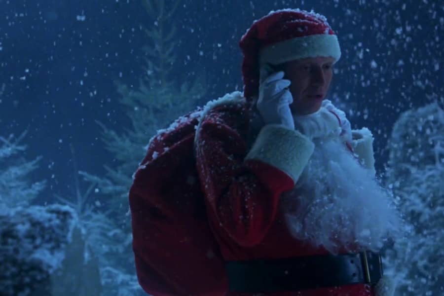 man in Santa Suit talks on a cell phone in the snow