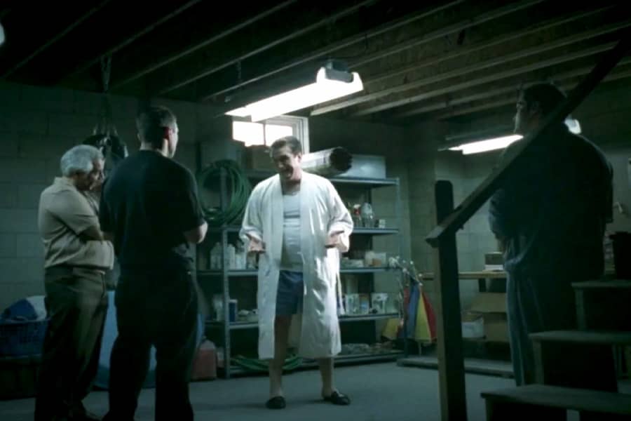a mob boss in a bathrobe meets with his guys in a basement