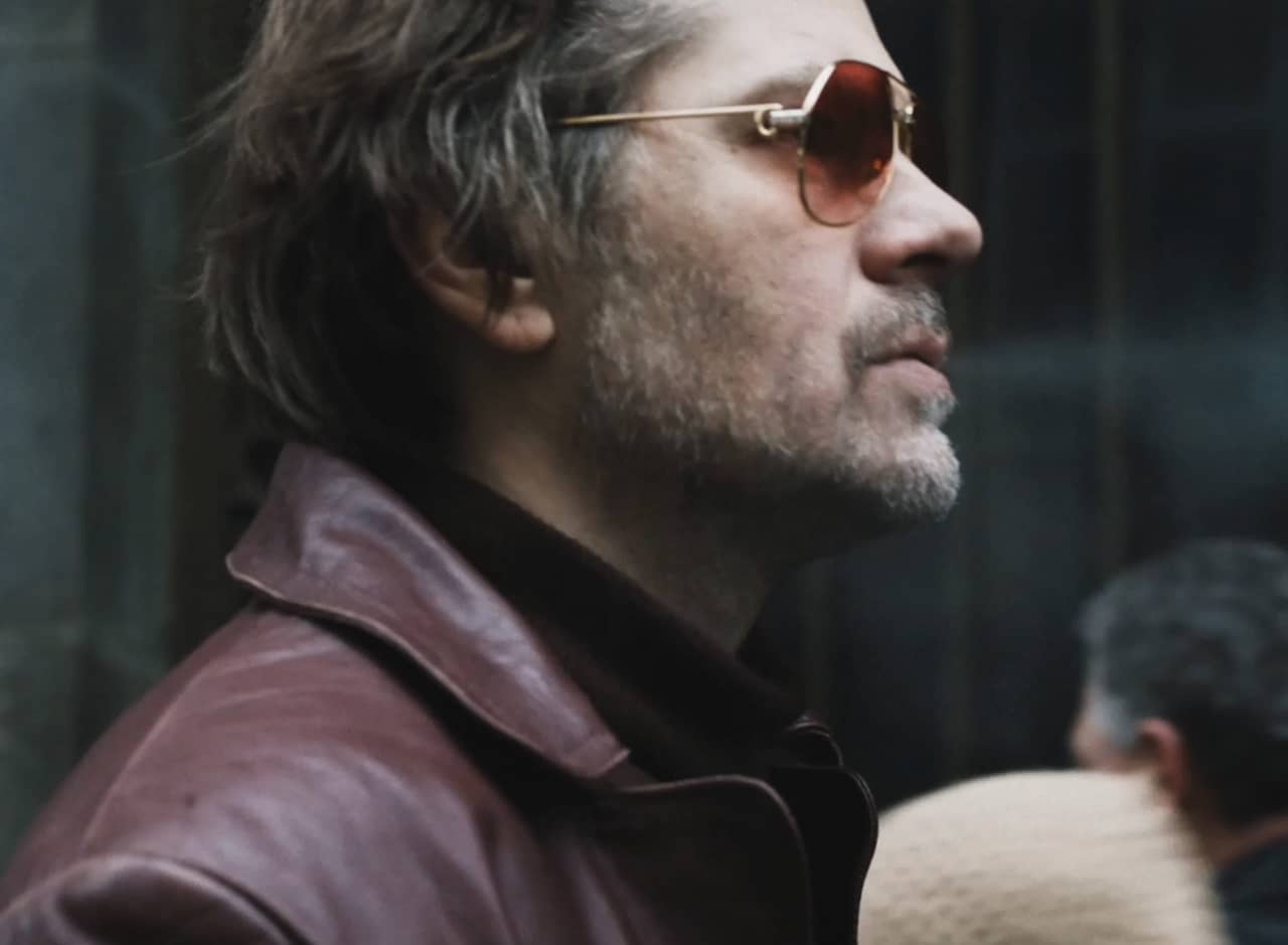 detective Gregor Anghel walking down the street, wearing sunglasses and a leather jacket