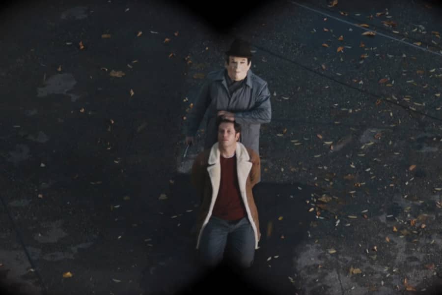 binocular view of a man in a mask holding his partner hostage