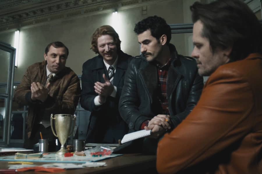 two detectives with trophies clap at Gregor and his new partner while they are looking at a Monopoly board