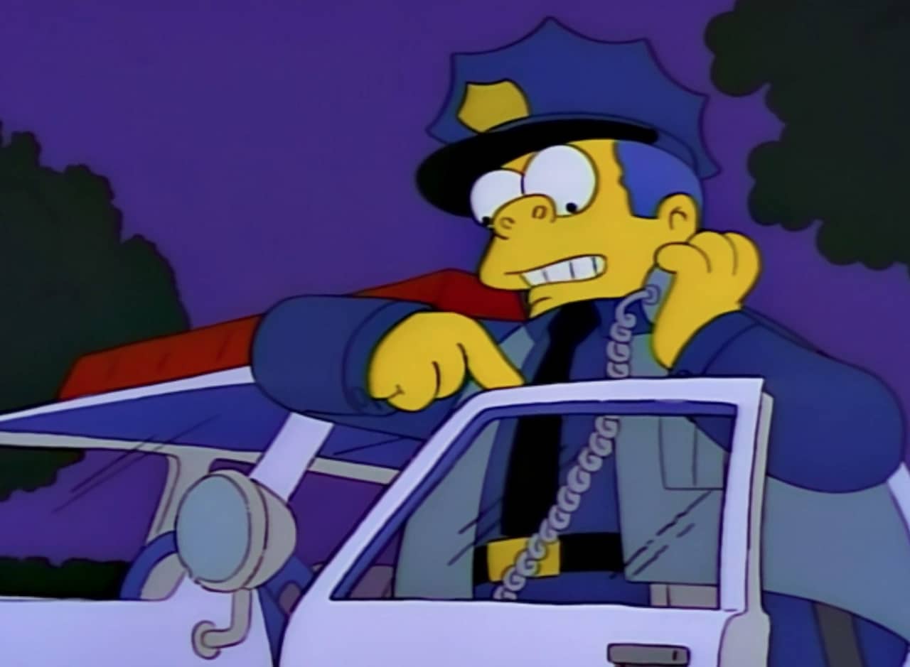 Chief Wiggum talks on his radio outside his police car