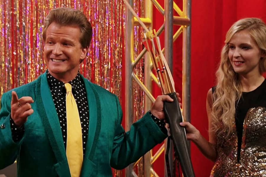 helper woman hands the host a bow and arrow